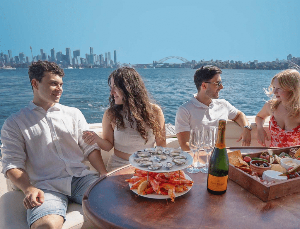 a group of people sitting at a table with food and drinks on a boat