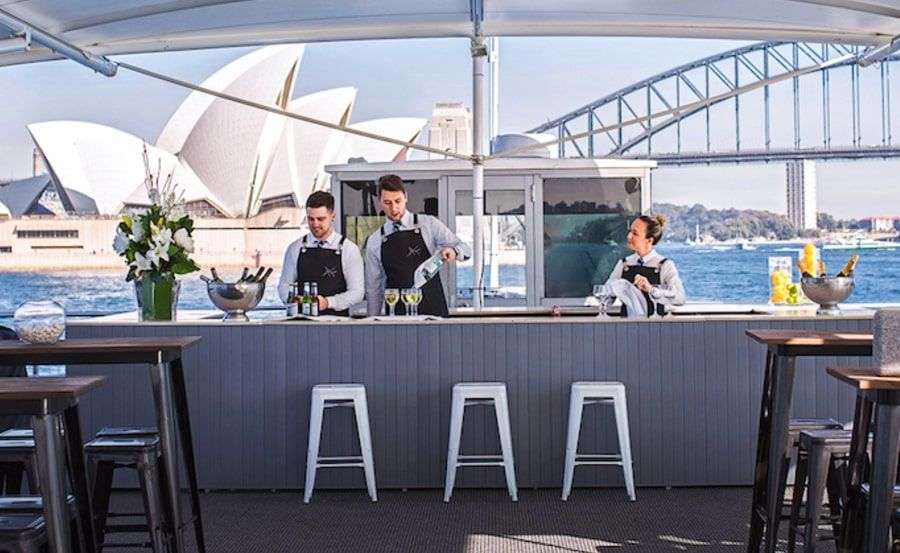 a group of people standing at a bar providing catering for boat hire party